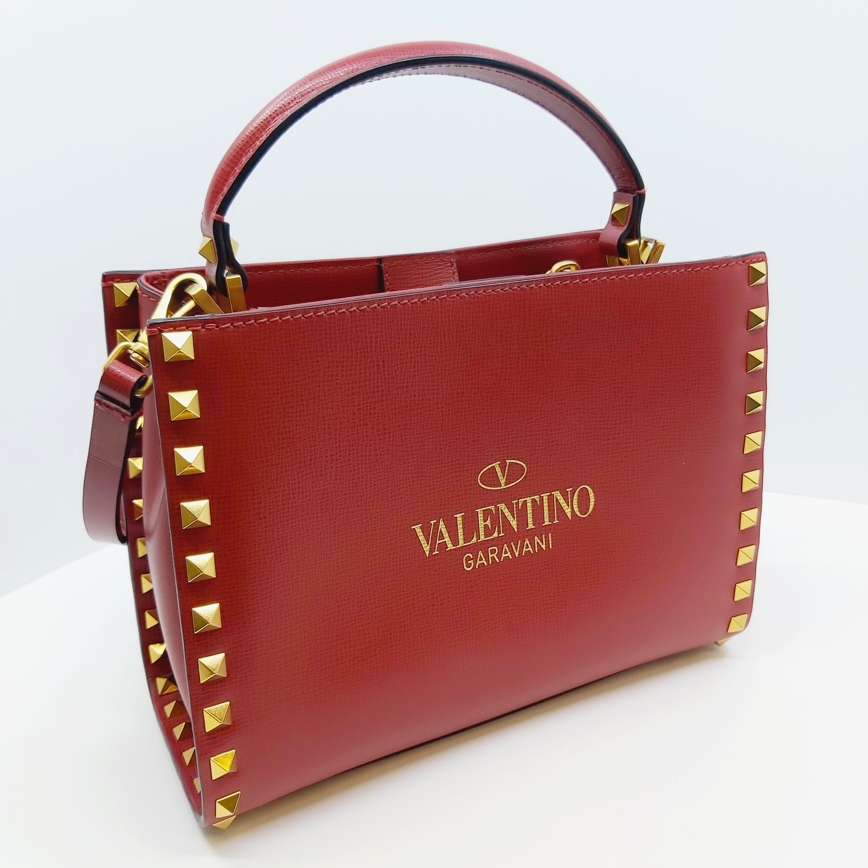Rote Valentino Rockstud Alcove Handtasche aus Leder, kleines Modell mit goldenen Nieten, Top-Handle, abnehmbarem Crossbody-Riemen, Logo vorne, Maße ca. 22x16x9 cm, luxuriös und elegant, inklusive Box und Staubbeutel.
