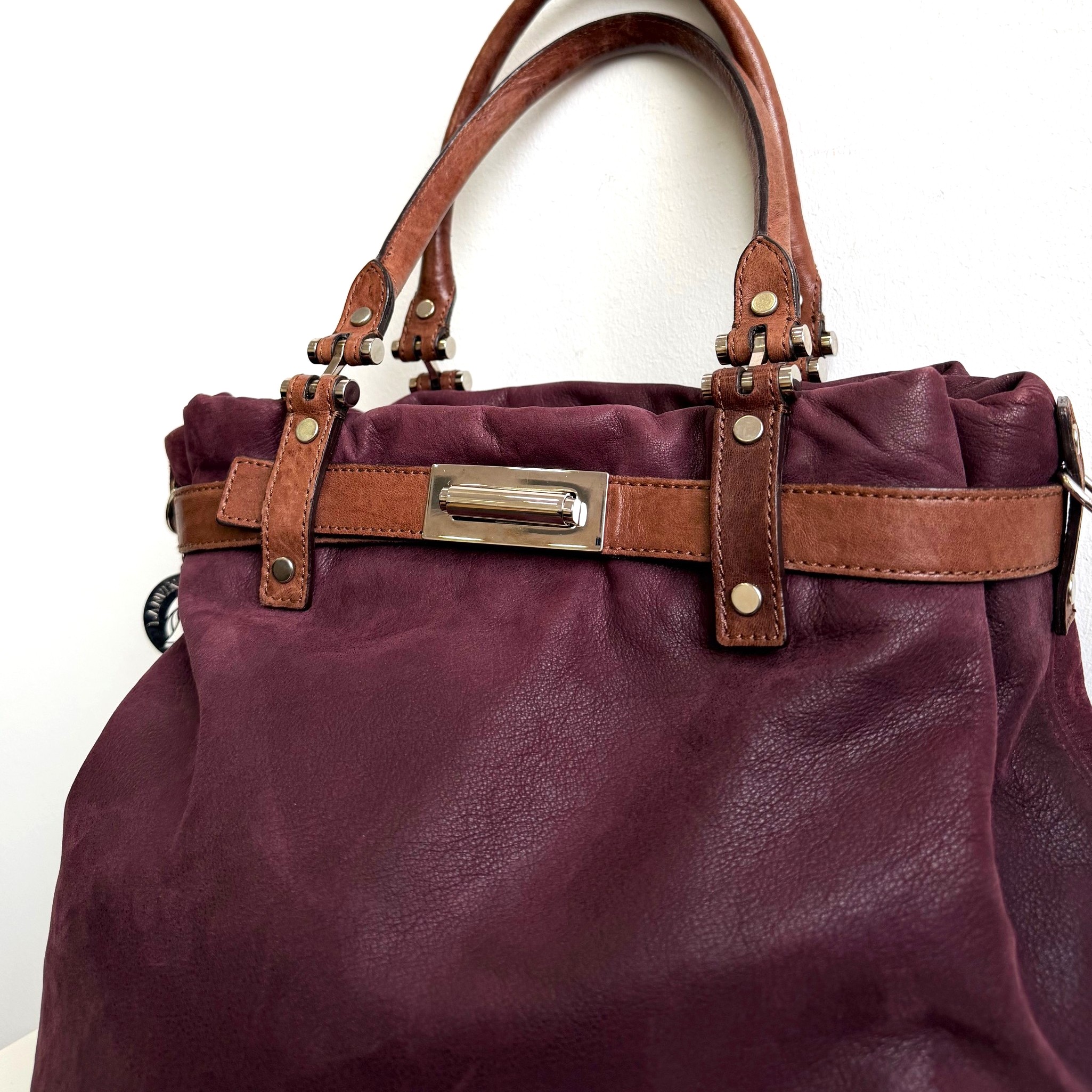 Lanvin Sac Kentucky Handtasche aus weichem bordeauxfarbenem Leder, braune Henkel und Riemen, silberfarbene Applikationen, ca. 38x36x13 cm, elegantes Design, hochwertig verarbeitet, Nahaufnahme der Details.