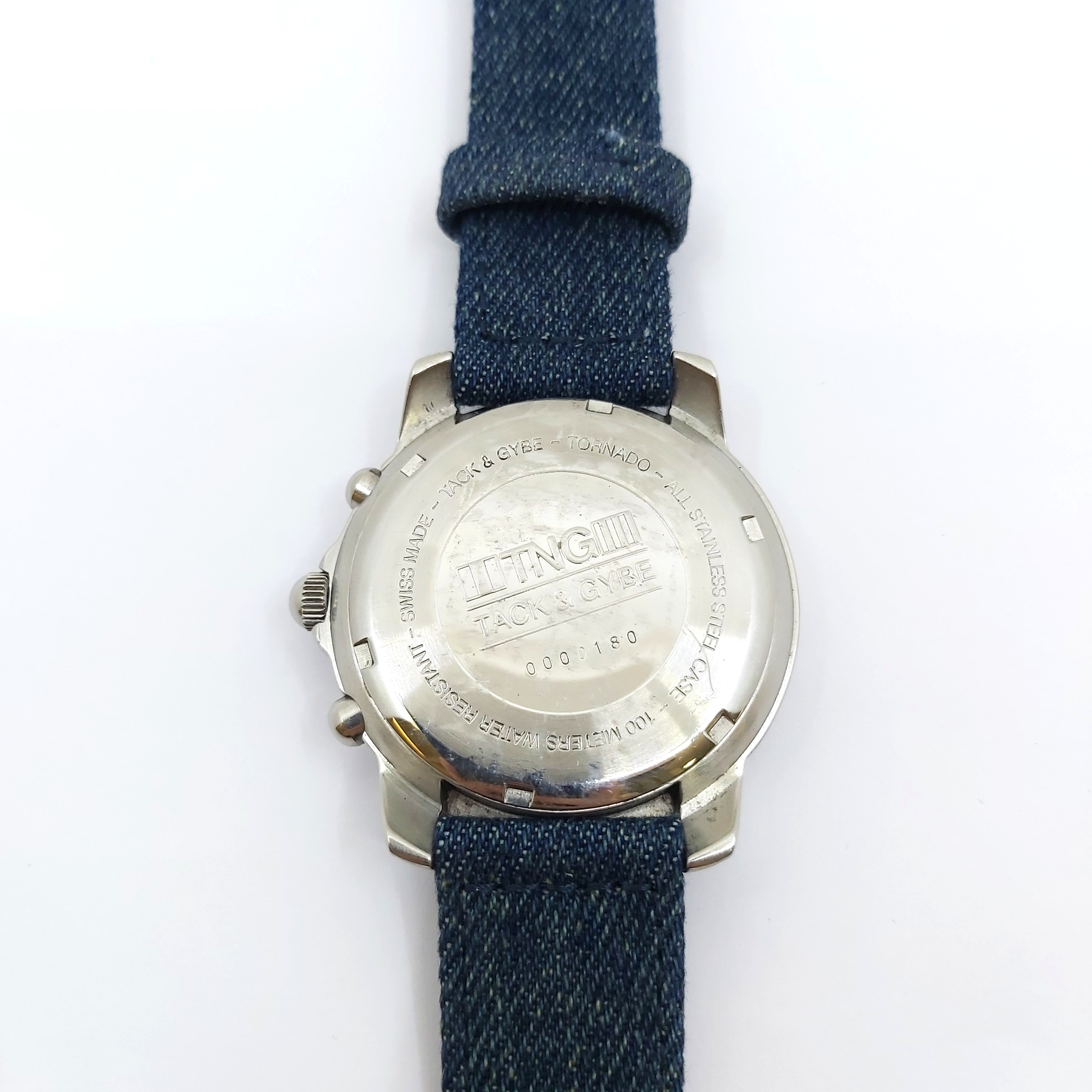Armbanduhr TNG Tornado Watch von 1999, Rückseite aus Edelstahl mit Gravur, blaues Textilband mit Faltschließe, altergemäße Tragespuren sichtbar, Sammlerstück, geprüfte Qualität, hochwertige Vintage Quarzuhr.