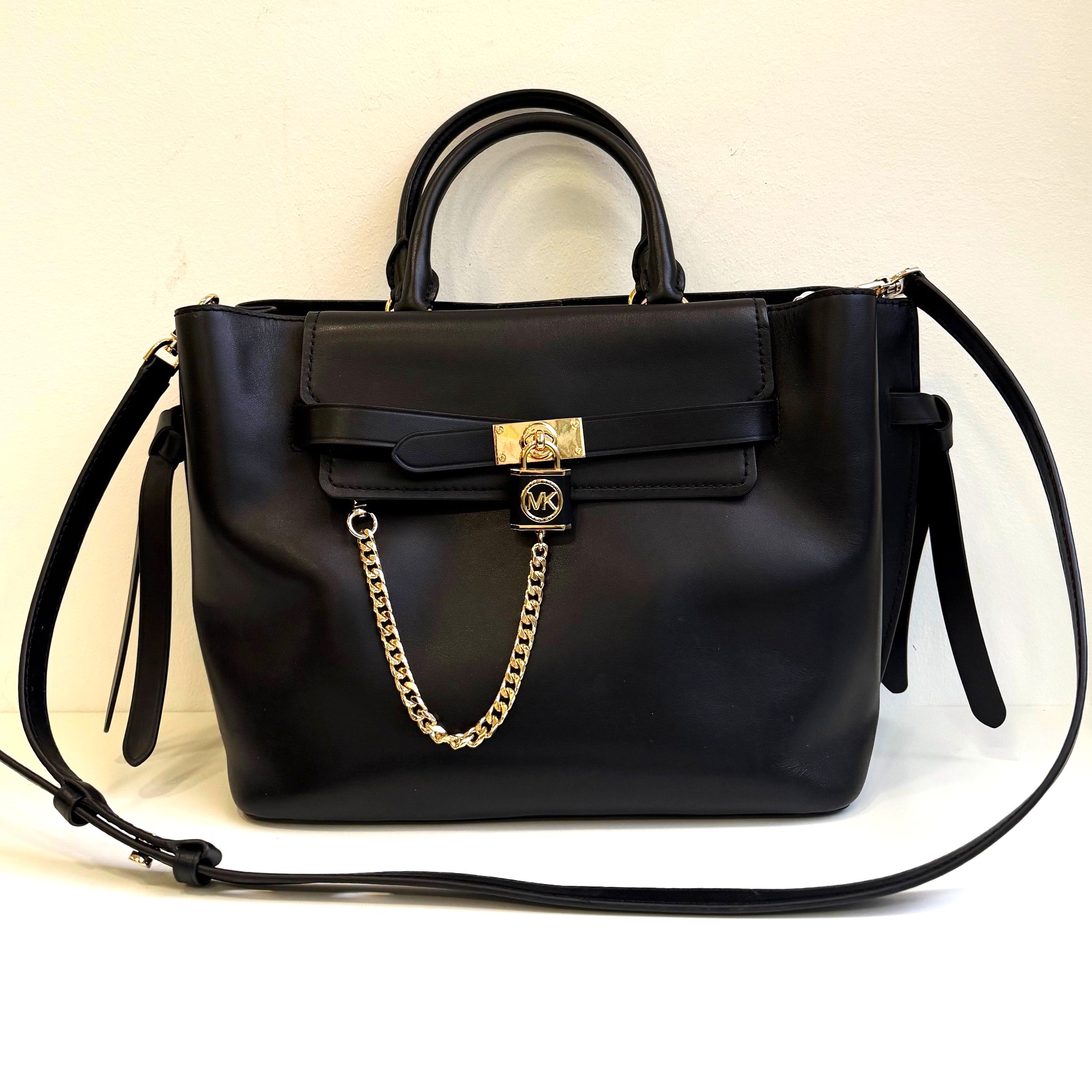 Schwarze Michael Kors Handtasche aus Leder mit goldfarbenen Details, Schmuckschloss, abnehmbarem, verstellbarem Schultergurt und Kettenapplikation, ca. 34x23x17 cm, dezente Gebrauchsspuren, luxuriöses Design.