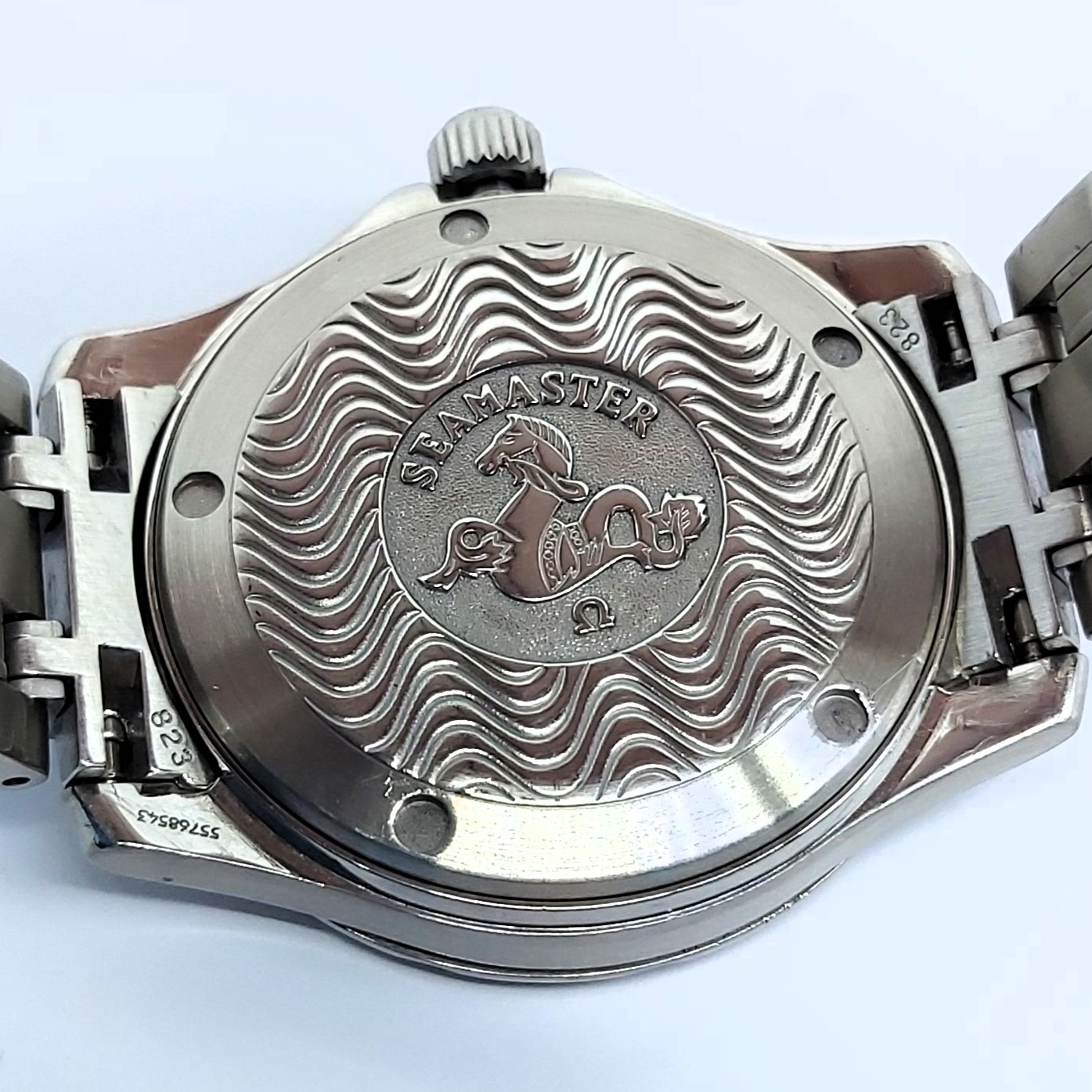 Detailaufnahme vom Gehäuseboden einer Omega Seamaster Omegamatic, quarzgesteuert, Edelstahl, wellenförmige Gravur mit Seepferdchen, sichtbare Gebrauchsspuren, verschraubte Krone, Gliederarmband, hochwertige Verarbeitung