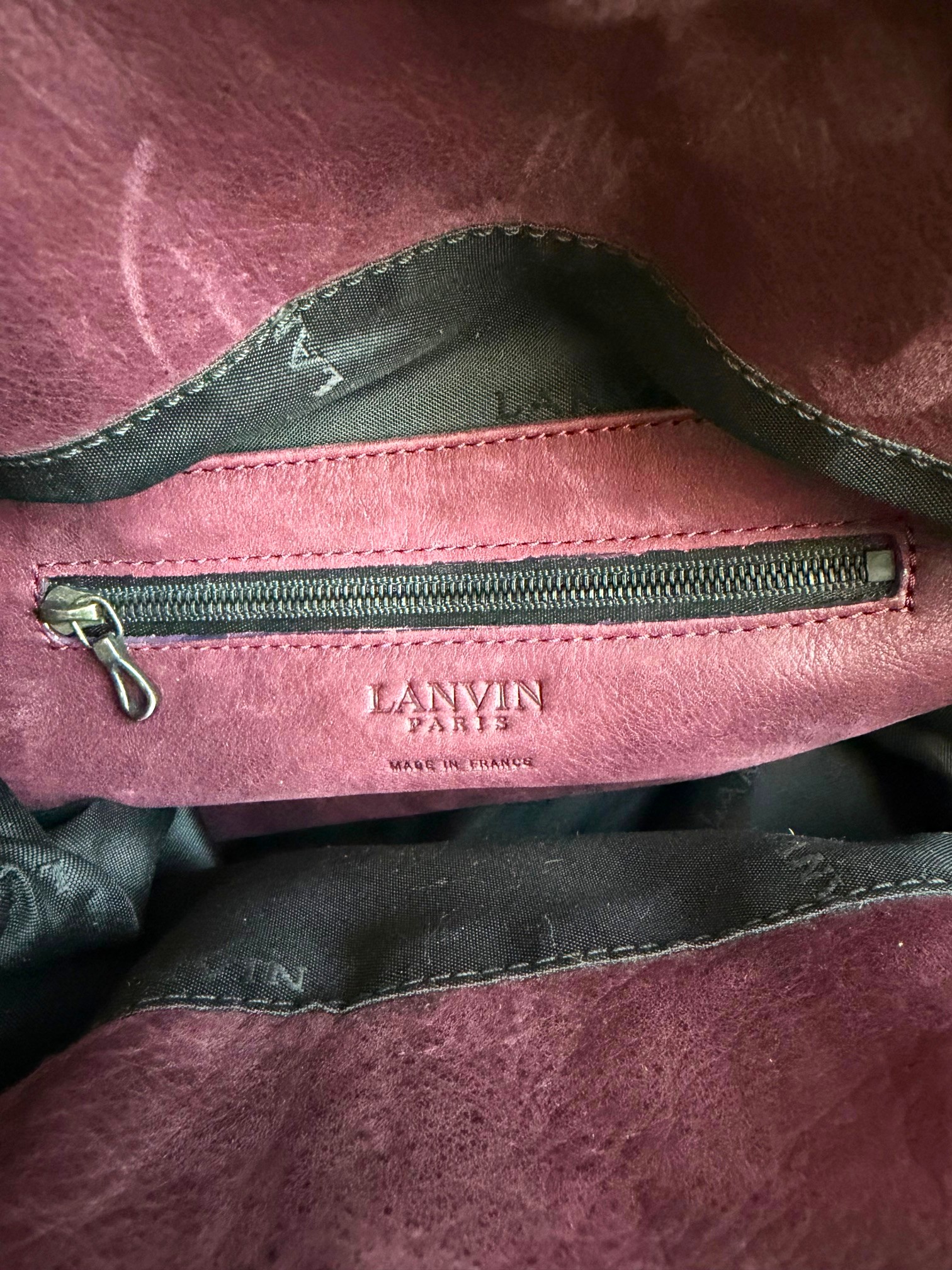 Innenansicht der Lanvin Sac Kentucky Handtasche aus weichem bordeauxfarbenem Leder, sichtbares Innenfutter, Reißverschlussfach mit silberfarbenem Zipper und geprägtem Logo, Maße ca. 38x36x13 cm.