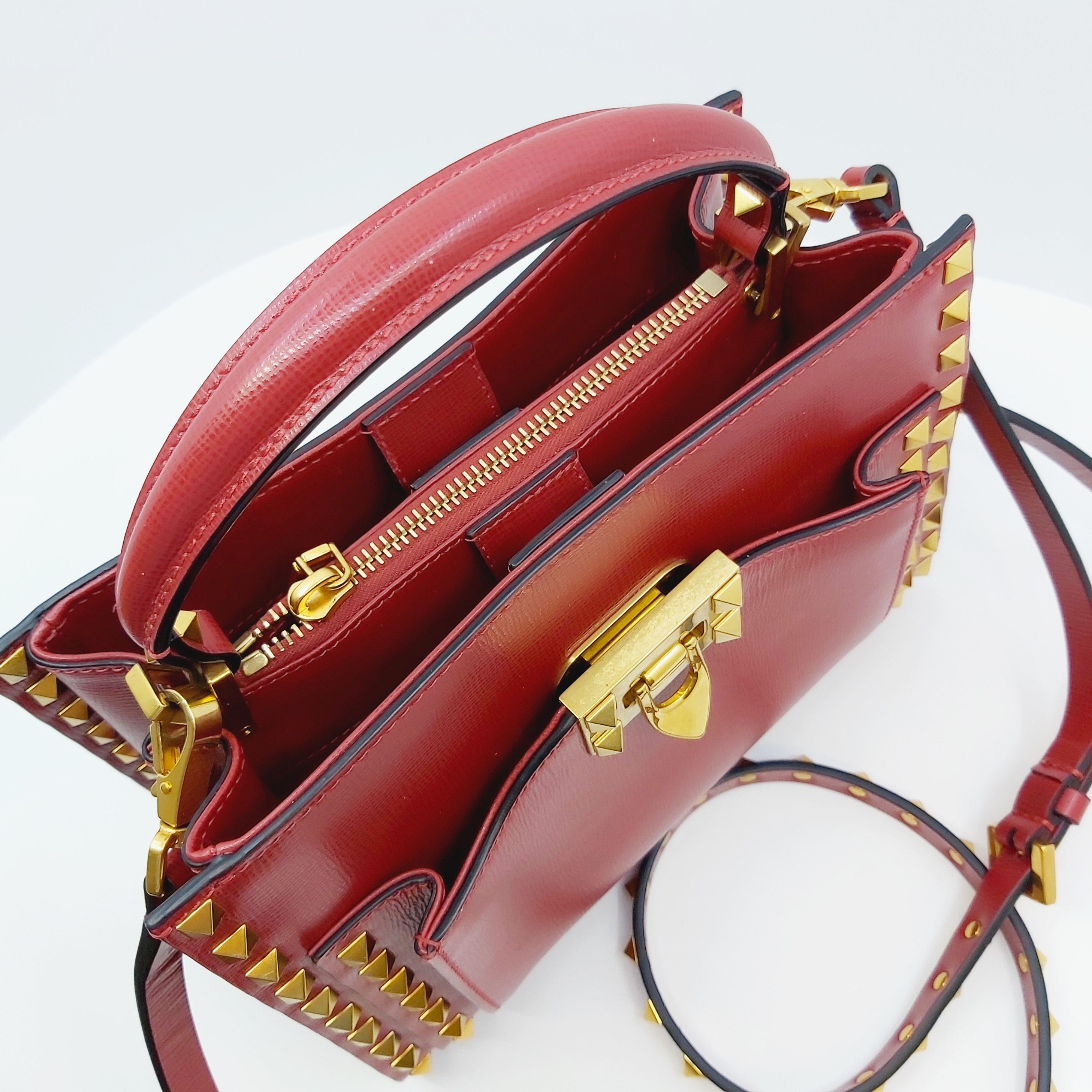 Rote Valentino Rockstud Alcove Small Leder-Handtasche mit goldenen Nieten, Top-Handle, verstellbarem Crossbody-Riemen, goldfarbenem Schloss und Reißverschluss, Maße 22x16x9 cm, inklusive Box, Staubbeutel und Ersatznieten.