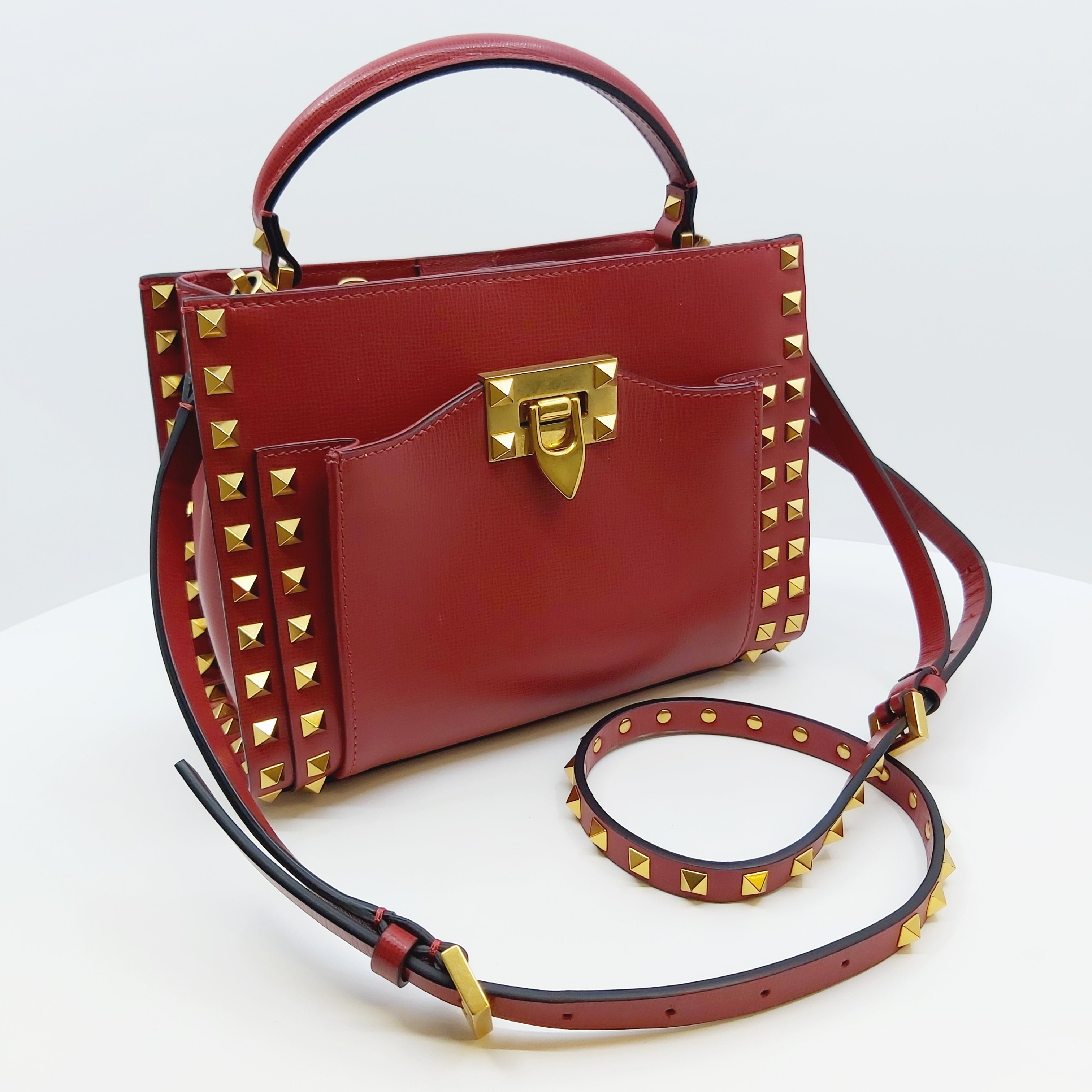 Rote Valentino Rockstud Alcove Small Lederhandtasche mit Goldnieten, Top-Handle und abnehmbarem, verstellbarem Schulterriemen, goldener Schließe, Maße ca. 22x17x9 cm, inkl. Box, Staubbeutel und Ersatznieten.